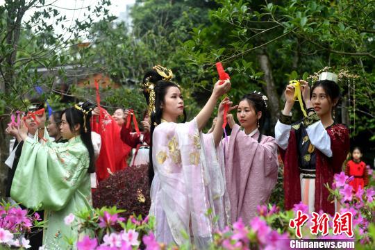 福建汉服少女将将写有对春日祝福的彩带系在百花枝头，共同送上美好的祝愿。　吕明 摄