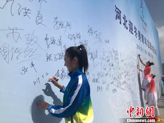 图为河北迎冬奥青年志愿者、张家口机械工业学校教师游洋在启动仪式现场主题背景墙上签名。　宋敏涛 摄