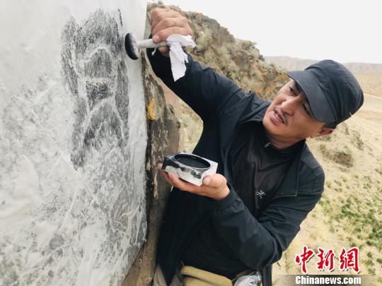 图为杜成峰按照岩画线条走向用拓包开始描边。　朵丹 摄