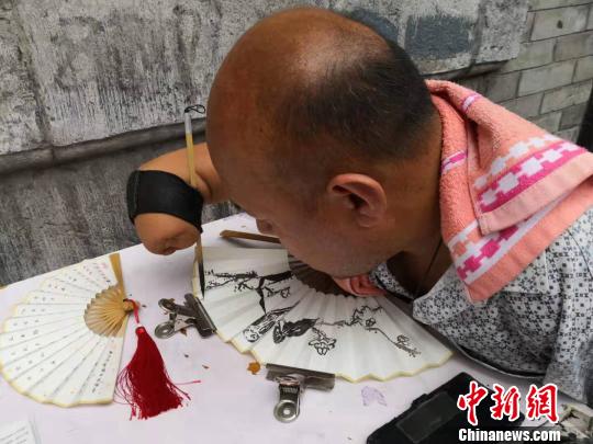 贾维军在扇面上写字。　阿琳娜 摄
