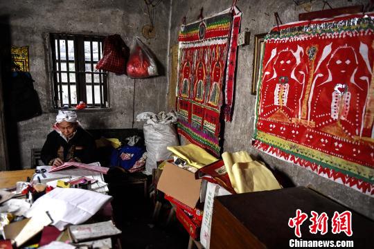 盘良安的“工作室”内堆满了祭祀用的道具、典籍，墙上张贴着盘王图。　李凌 摄