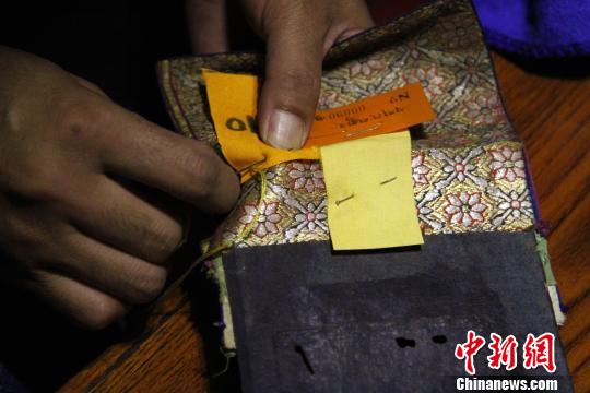 图为罗布林卡管理处工作人员将编号缝在古籍外侧。　赵朗 摄