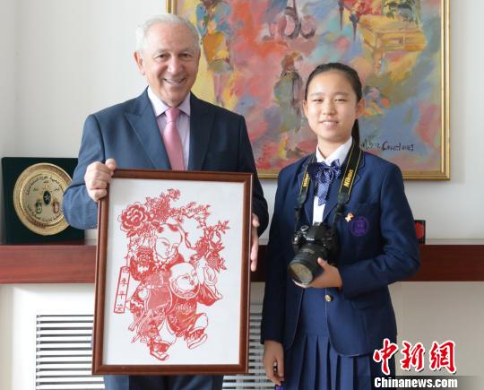 “2019丝路新语？中外文化小使者巡礼”活动在京启动。图为中国文化小使者向摩洛哥王国驻华大使阿齐兹？梅库阿尔赠送中国剪纸。主办方供图