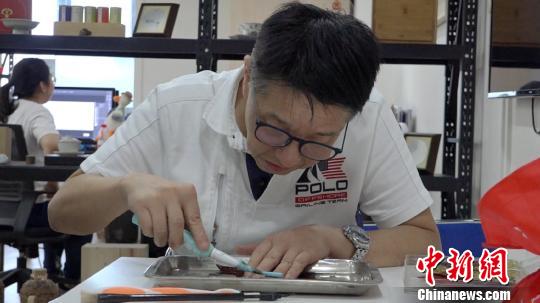 李亚非用电动牙刷正在制作叶雕作品。　徐明睿 摄