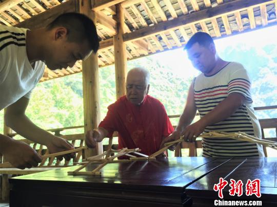 图为黄春财与儿子、孙子共同演示木拱廊桥搭建。　叶茂 摄