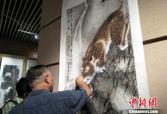 观众欣赏六尺国画挂轴《豹子觅泉图》。主办方供图