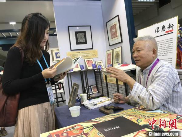 秀洲农民画画家缪惠新和参观者交流。供图