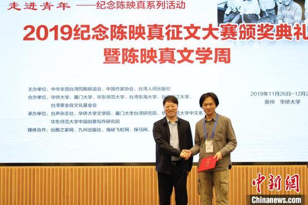 中华全国台湾同胞联谊会副会长郑平(左)为“陈映真思想与创作”论文一等奖获得者张立本颁奖。　刘沛 摄