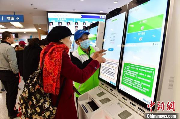 资料图：患者在指导下使用人脸识别系统预约专家号。