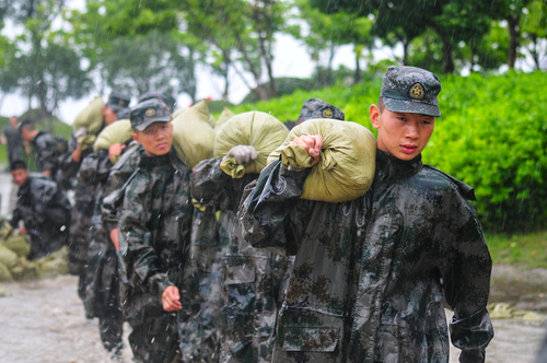 图为在安徽合肥巢湖任务区官兵在暴雨中扛运沙袋，加固堤坝。（王文洲 摄）