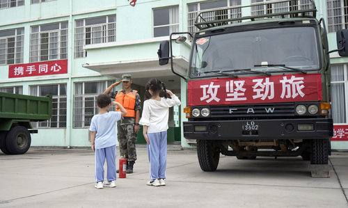 图为在学校宿营点，小学生向抗洪官兵官兵敬礼表达谢意的画面。（付少旋）
