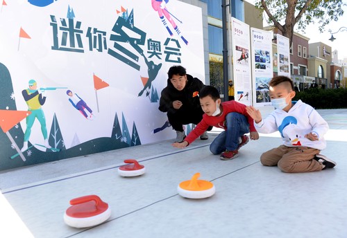 民众在冬奥体验互动区体验冰壶迷你冬奥活动。