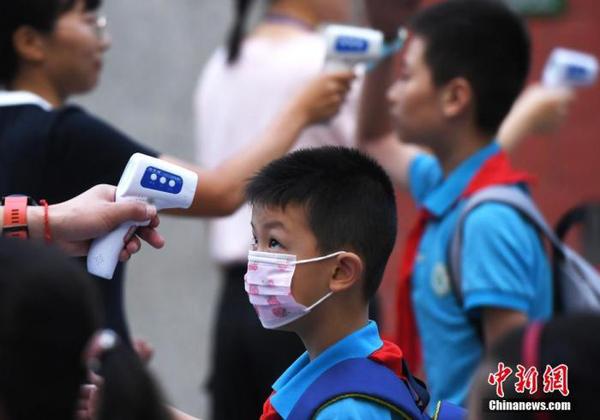 资料图：工作人员为学生测量体温。 中新社记者 陈超 摄