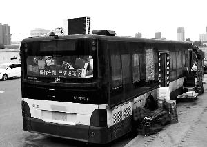 路边停放的公交车顶上的空调十分显眼，旁边码放着座椅、遮阳棚、啤酒等物。康佳/摄